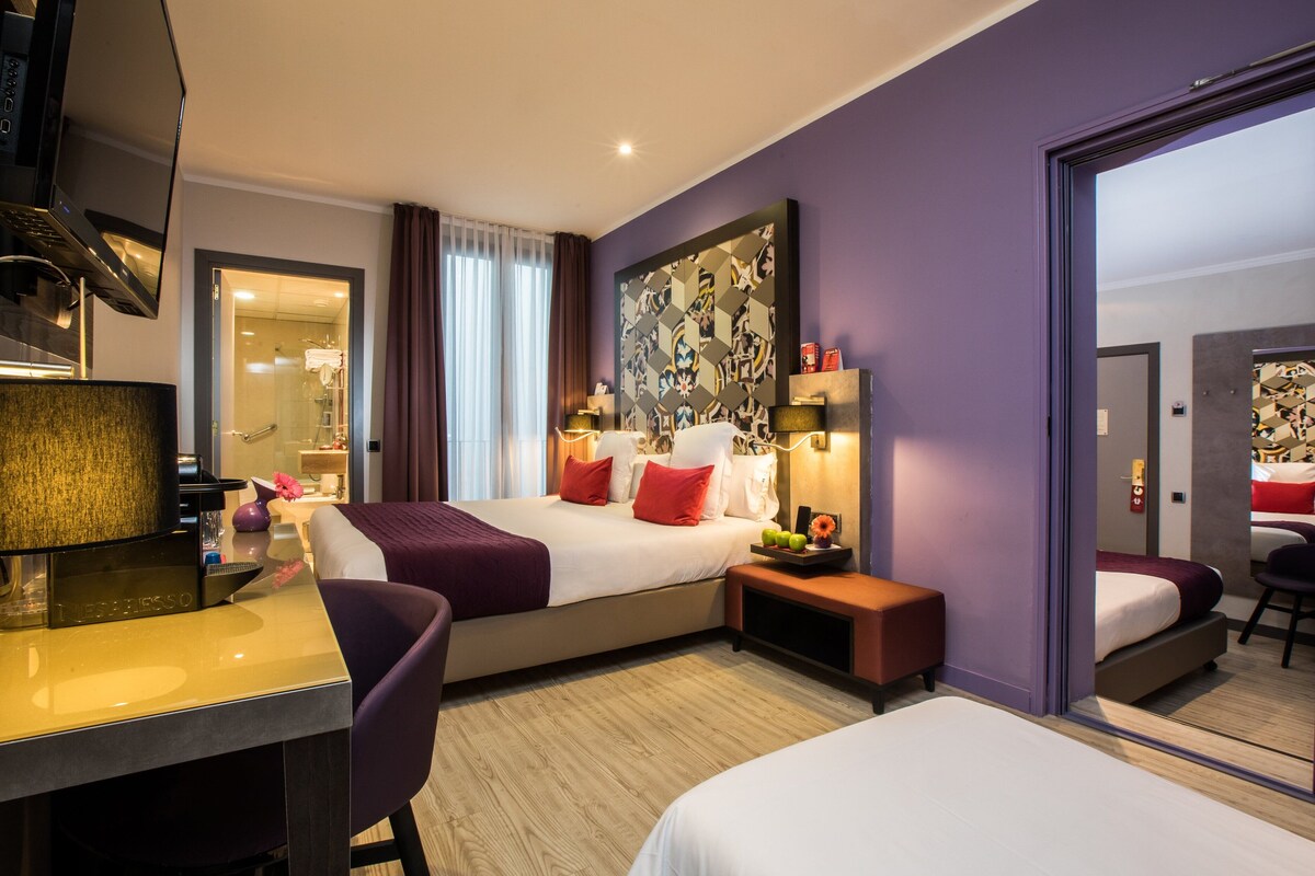 A modern hotel room with a large bed, a desk, and a mirror.