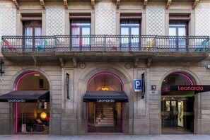 Fachada de edifício com um letreiro 'Leonardo' em destaque, uma varanda com cadeiras e uma escadaria que leva a uma entrada.