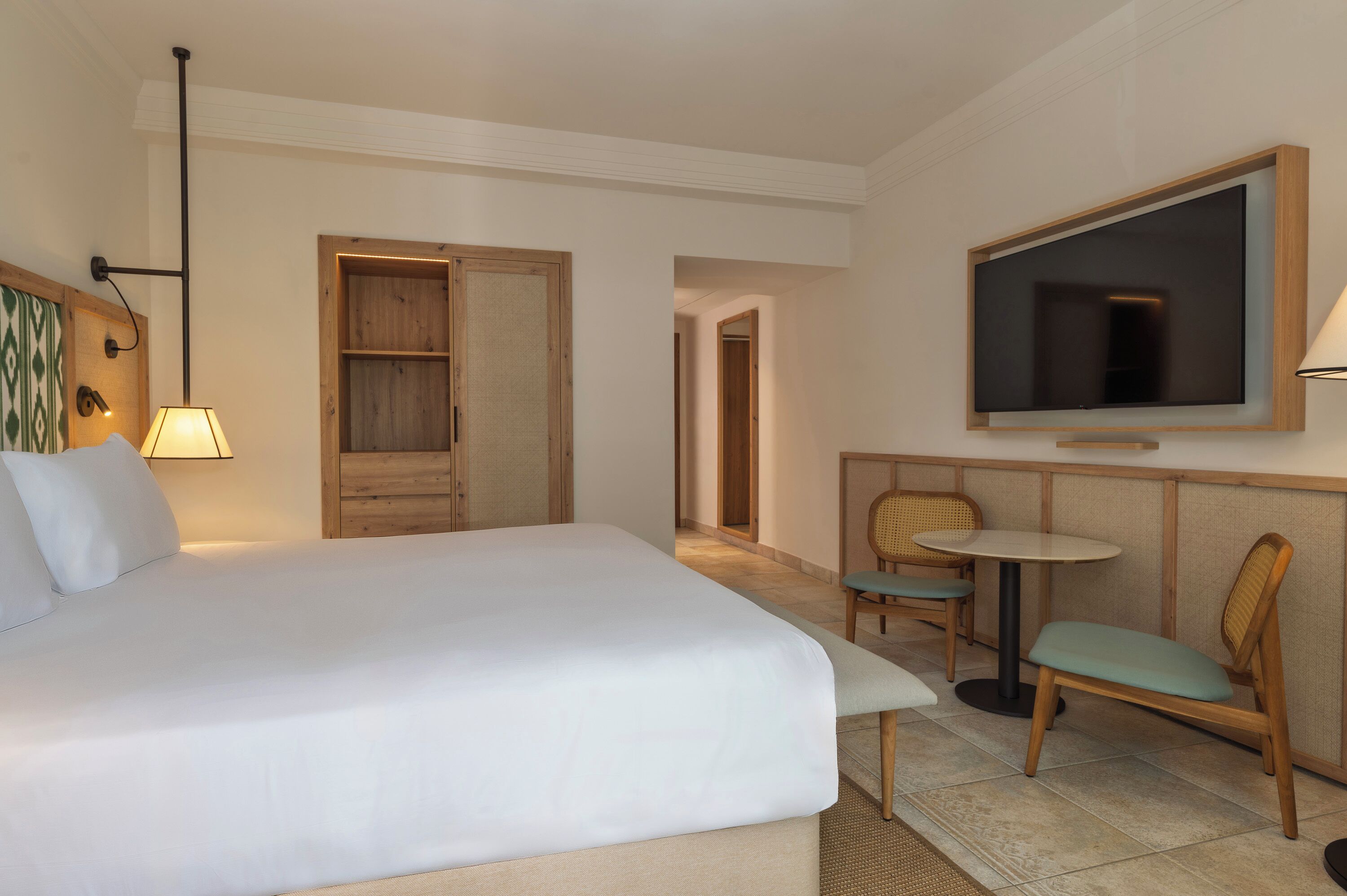 A hotel room with a bed, a TV, a desk, and chairs.