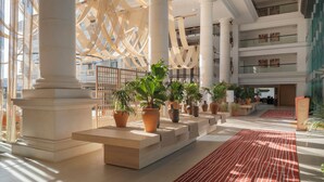 Un hall amplio con techos altos, columnas imponentes y plantas en macetas.
