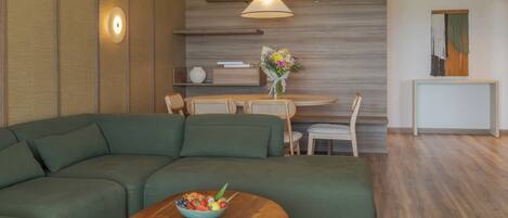 Una sala de estar moderna con un sofá seccional, una mesa de comedor con sillas, una pared decorativa de madera y una lámpara colgante.