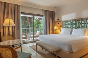 A hotel room with a large bed, a table, a bench, a chair, a lamp, and a view of the outdoors. - Sarena de Muro Resort Mallorca, part of Destination by Hyatt (Muro)