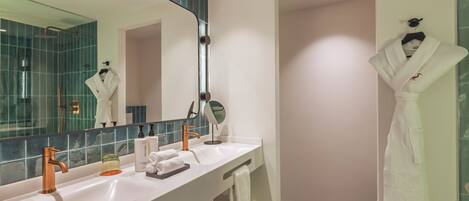 A modern bathroom with a large mirror, two sinks, a towel rack, and a robe hanging on the wall.