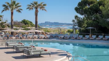 Una piscina techada, una piscina al aire libre, sombrillas
