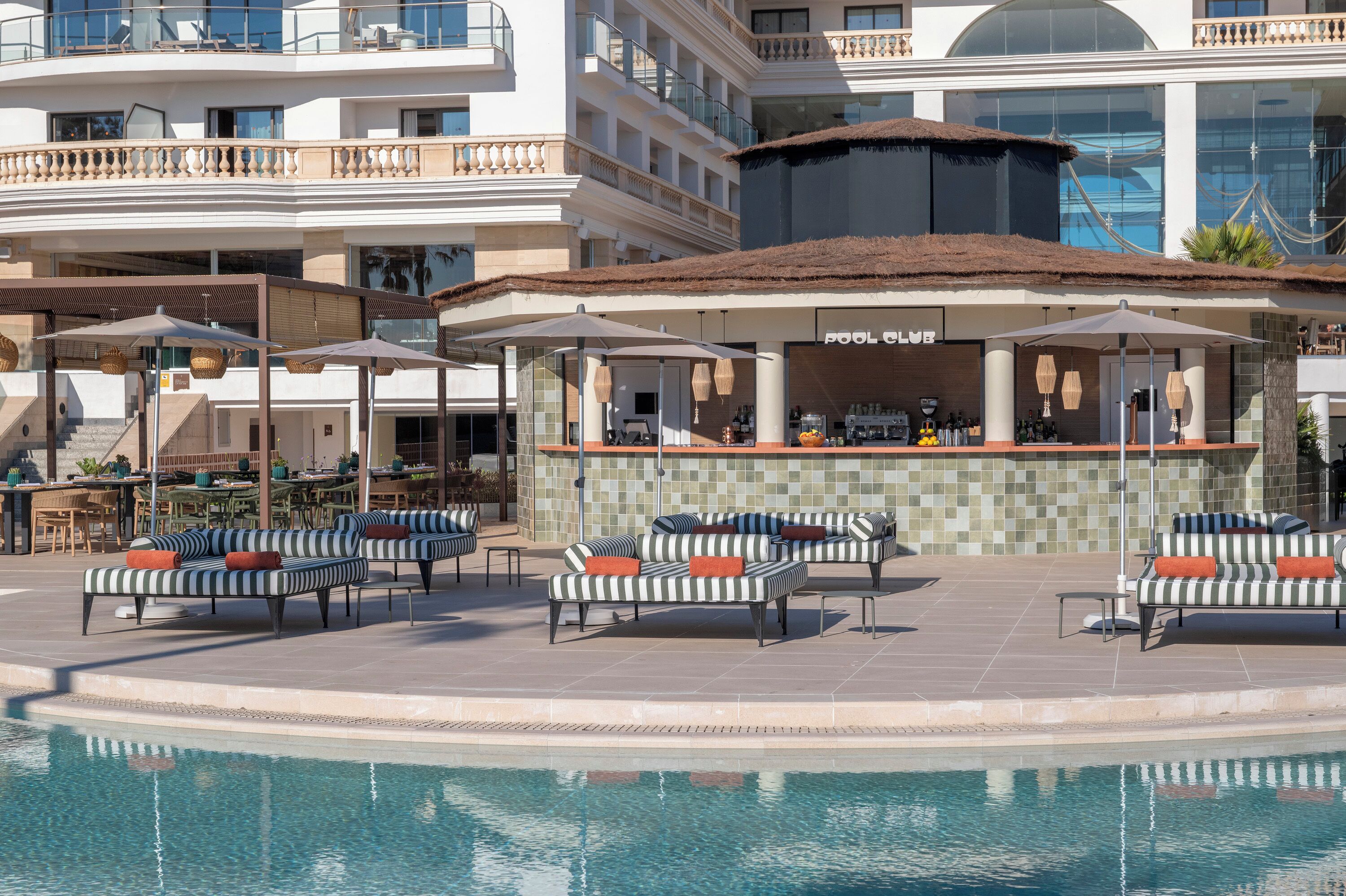 A poolside area with lounge chairs, a bar, and a pool.