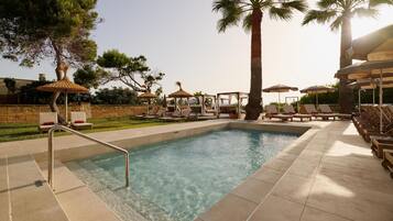 Una piscina techada, una piscina al aire libre, sombrillas