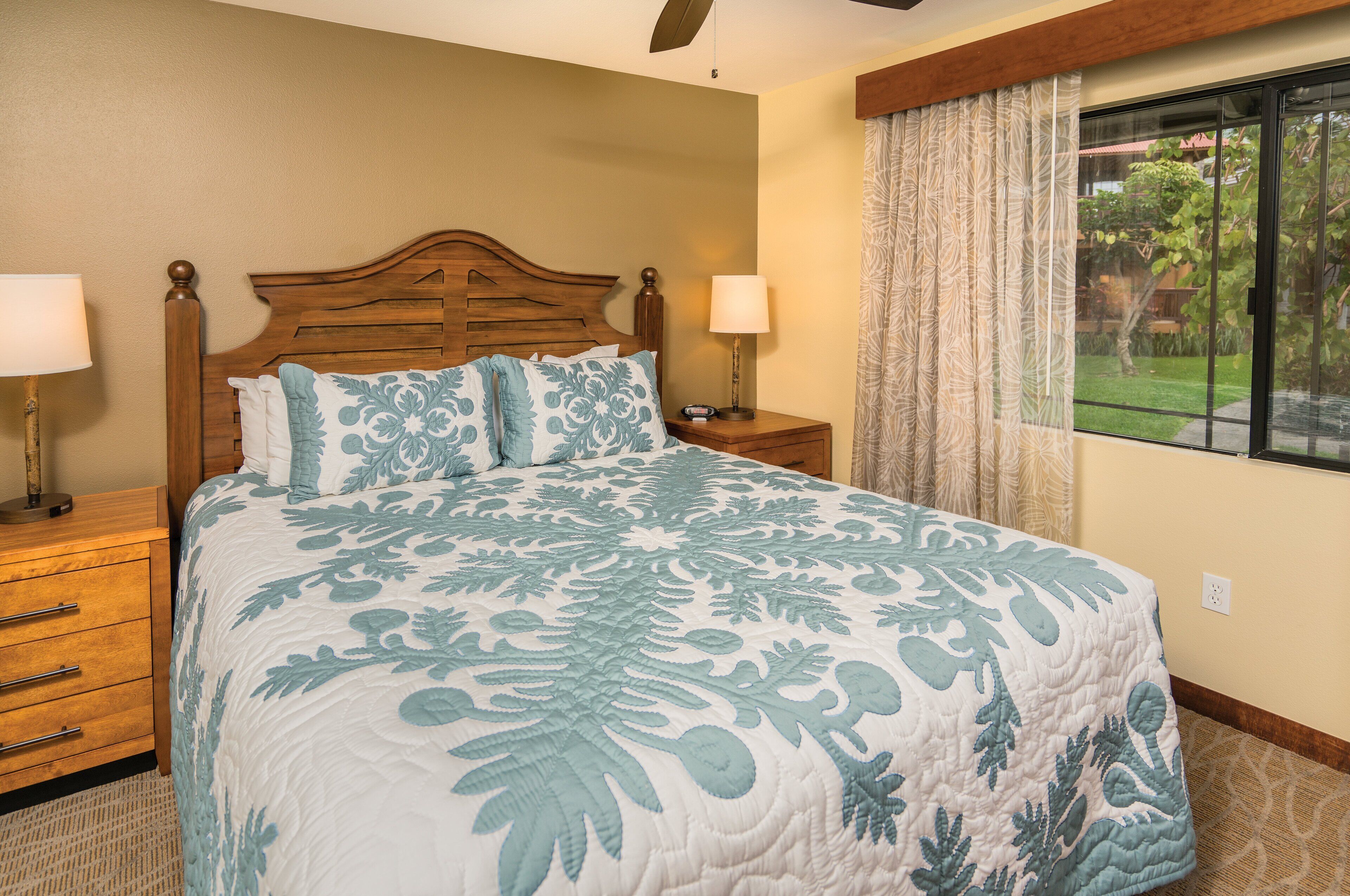 A bedroom with a large bed, wooden headboard, two bedside tables with lamps, and a window with curtains.