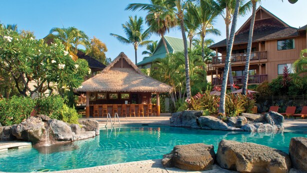 A resort pool with a thatched-roof hut, palm trees, and a multi-story building with balconies. - Club Wyndham Kona (Kailua-Kona)