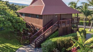 A wooden house with a red roof, a staircase, and a garden with various plants. - Club Wyndham Kona (Kailua-Kona)
