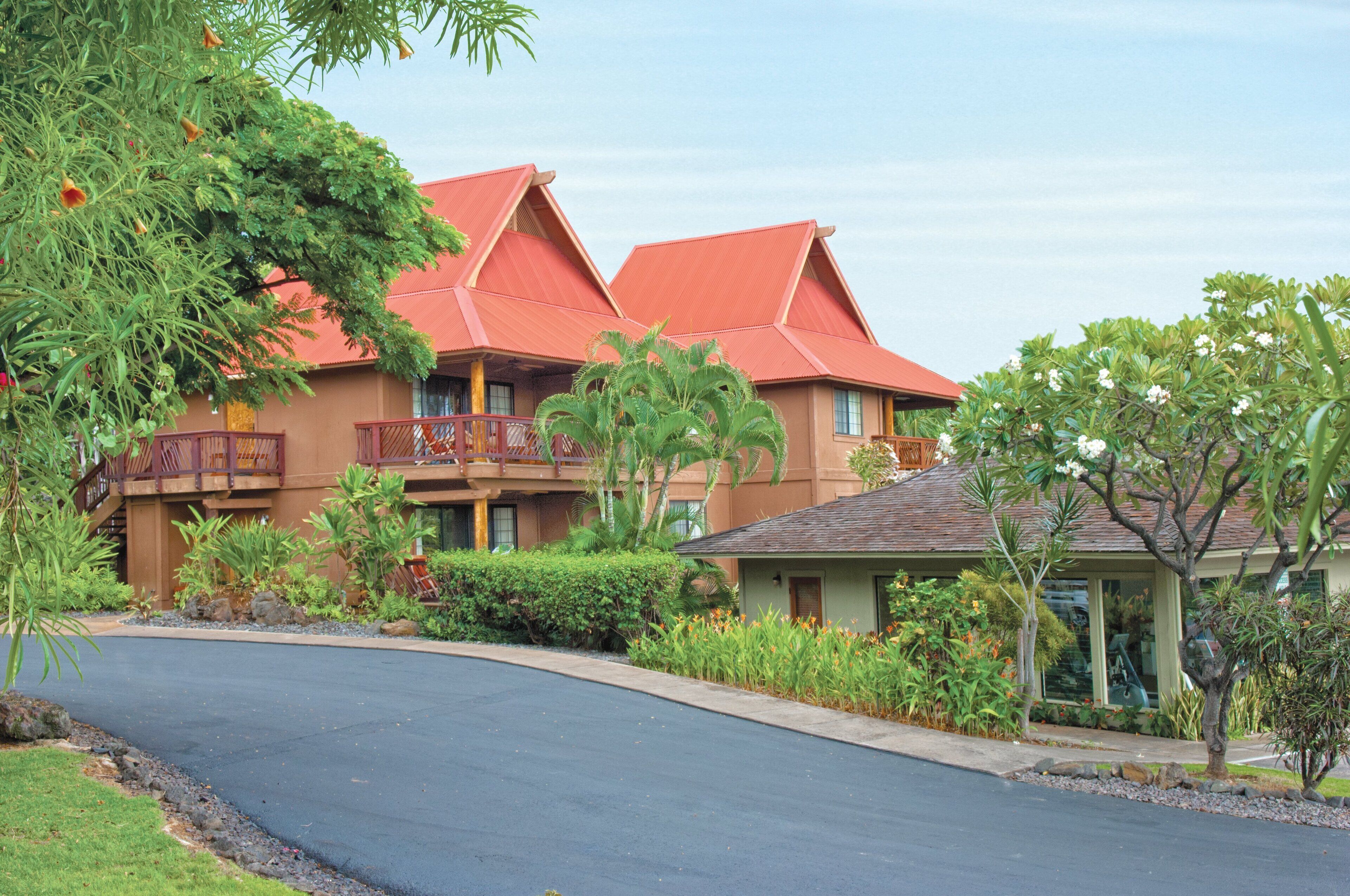 A resort with a red-roofed building, a curved driveway, and lush landscaping.