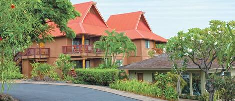 A resort with a red-roofed building, a curved driveway, and lush landscaping.