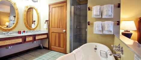 Une salle de bain avec une grande baignoire, deux lavabos avec miroirs, une douche et des serviettes accrochées au mur.