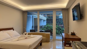 Une chambre d’hôtel équipée d’un lit, d’un bureau, d’une chaise et d’un balcon donnant sur un paysage verdoyant.