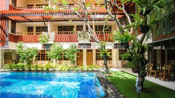 Un hôtel doté d’une piscine, d’un espace extérieur aménagé et d’une végétation luxuriante.