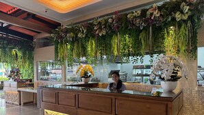 Un comptoir d’accueil doté d’un plateau en verre, de panneaux en bois et d’un éclairage décoratif.