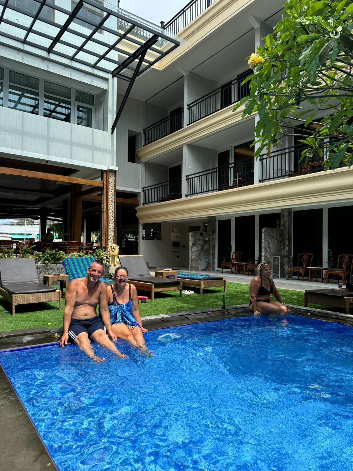 A pool area with lounge chairs and a building with multiple balconies.