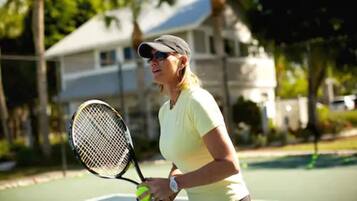 A tennis court with a house in the background.
