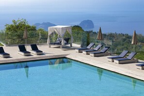 A poolside area with lounge chairs and a canopy, overlooking a body of water and greenery. - Nastro Azzurro Resort (Piano di Sorrento)