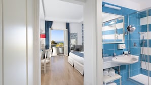 A modern hotel room with a wooden floor, a bed, a bathroom with blue tiles, a sink, and a mirror. - Atlantic Palace Hotel (Sorrento)