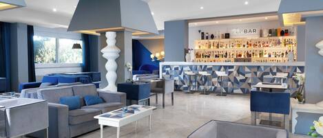 Een moderne bar met een geometrisch wandontwerp, zitgedeeltes en diverse flessen op planken.