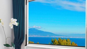 A room with a large window offering a view of the sea and distant mountains. - Atlantic Palace Hotel (Sorrento)