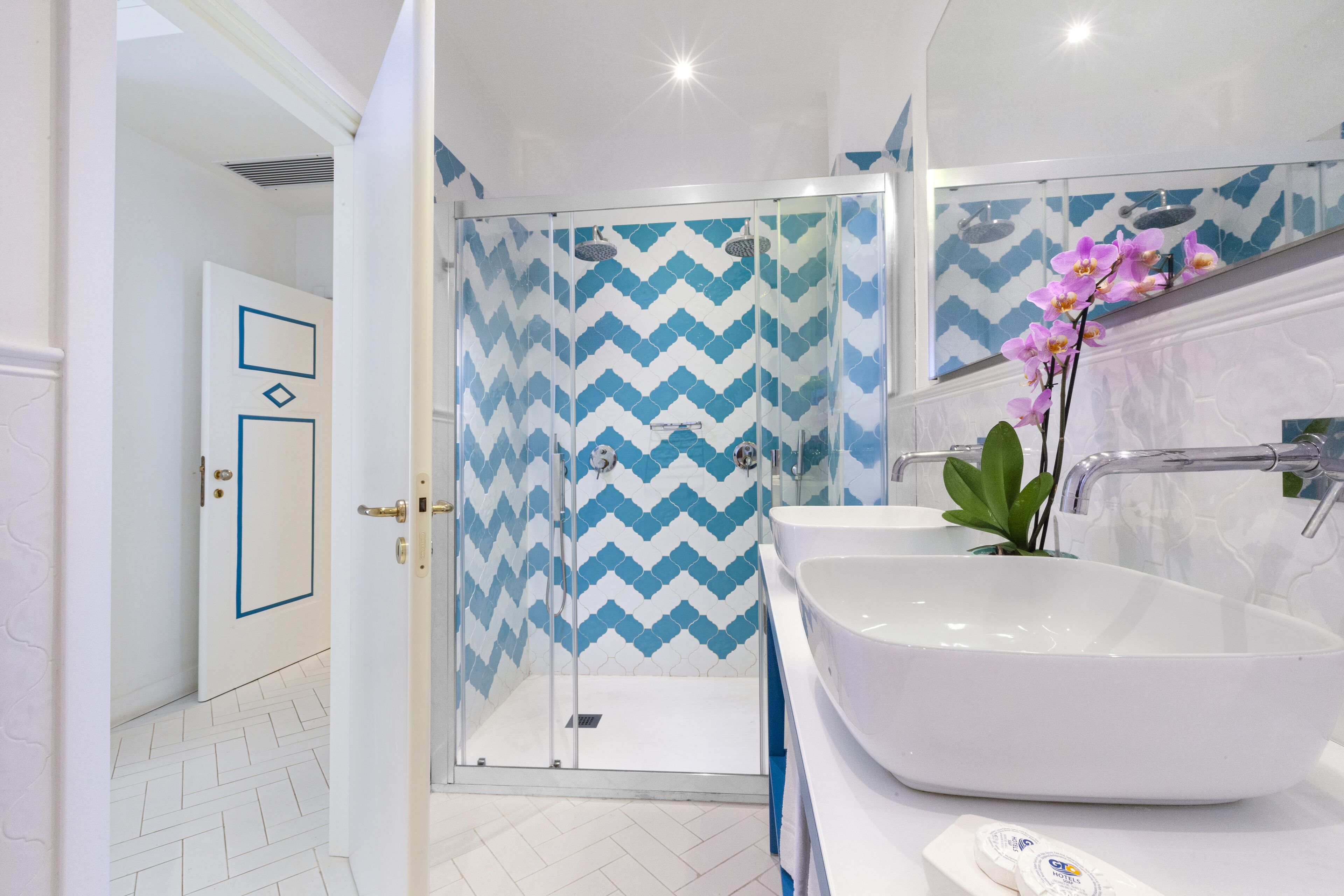Ein modernes Badezimmer mit einem großen weißen Waschbecken, einer Glasdusche und einem Spiegel über dem Waschbecken.