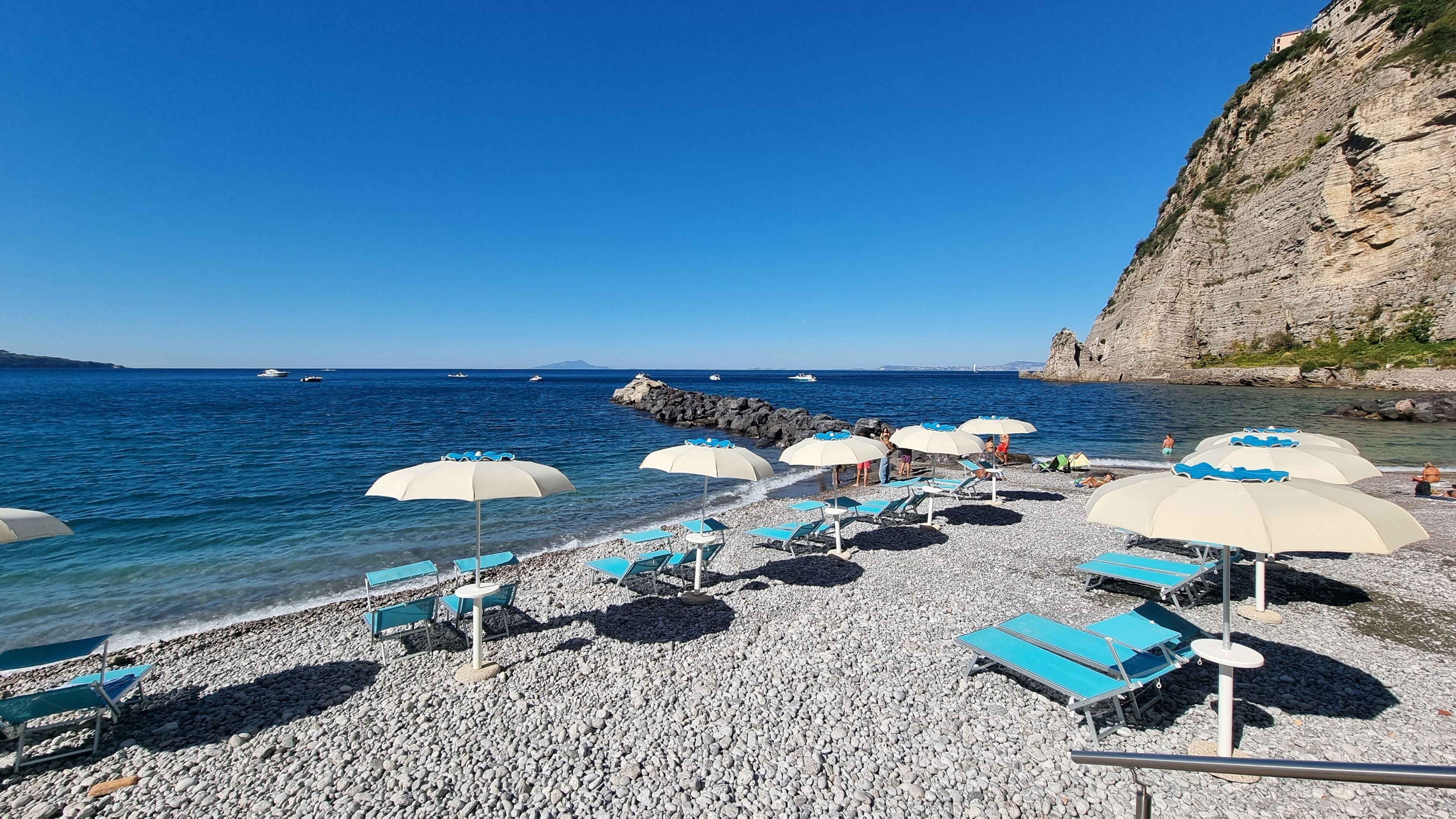Privat strand, svart sandstrand, solstolar och parasoller