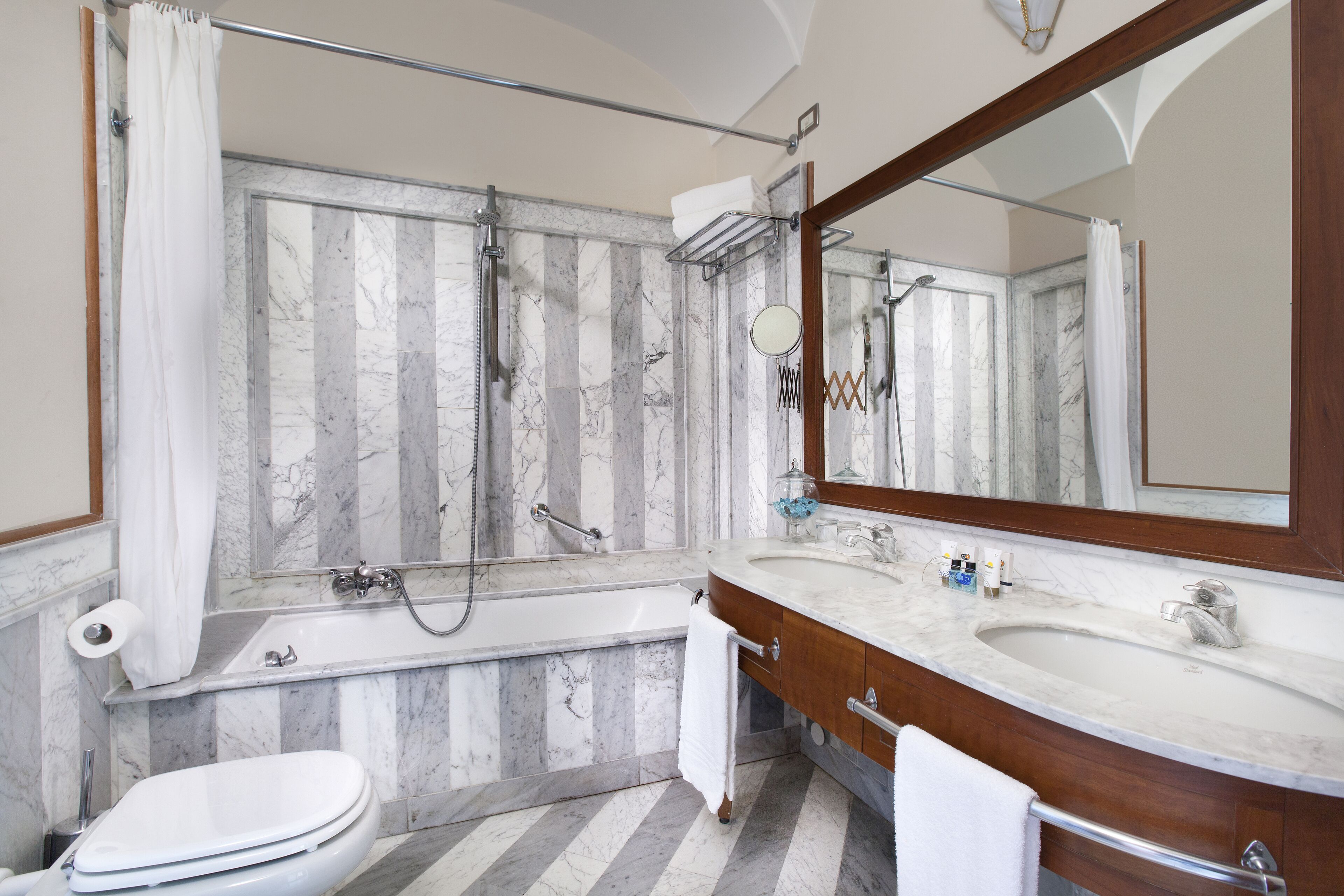 Ein Badezimmer mit Badewanne, Toilette, Waschbecken und einem großen Spiegel.