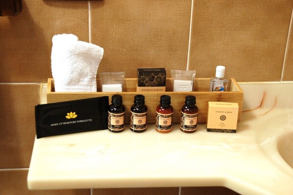 A bathroom vanity with a towel, a makeup remover, and several bottles of Ancient Earth body wash.