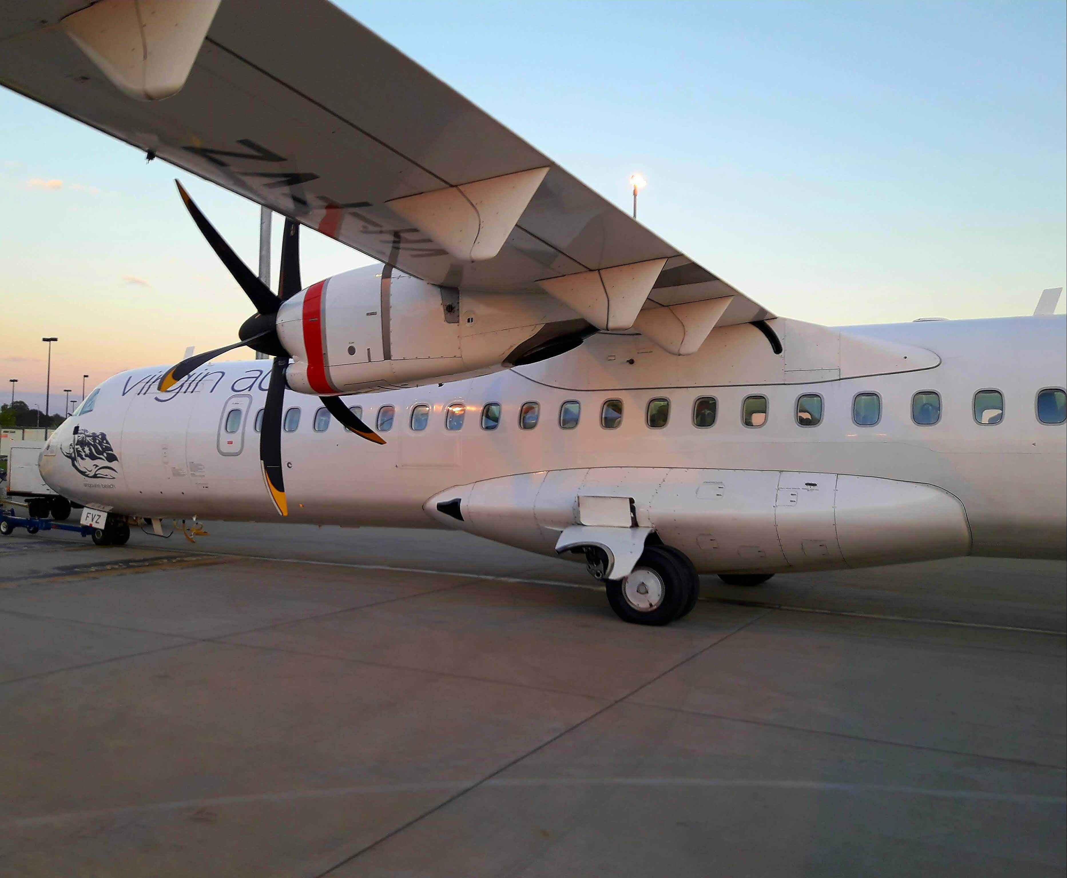 A stationary airplane with a propeller, parked on the tarmac.