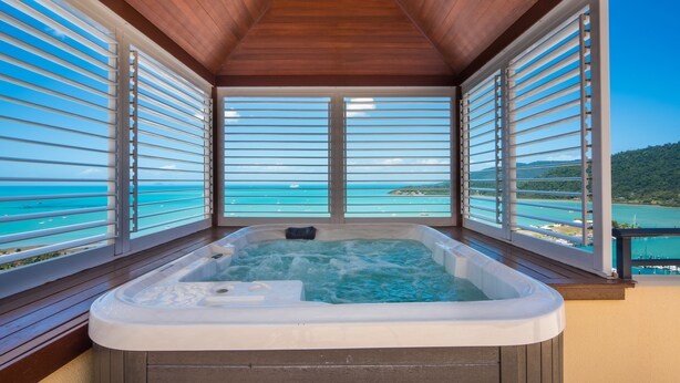 A hot tub with a wooden ceiling and large windows overlooking a turquoise sea. - Pinnacles (Airlie Beach)