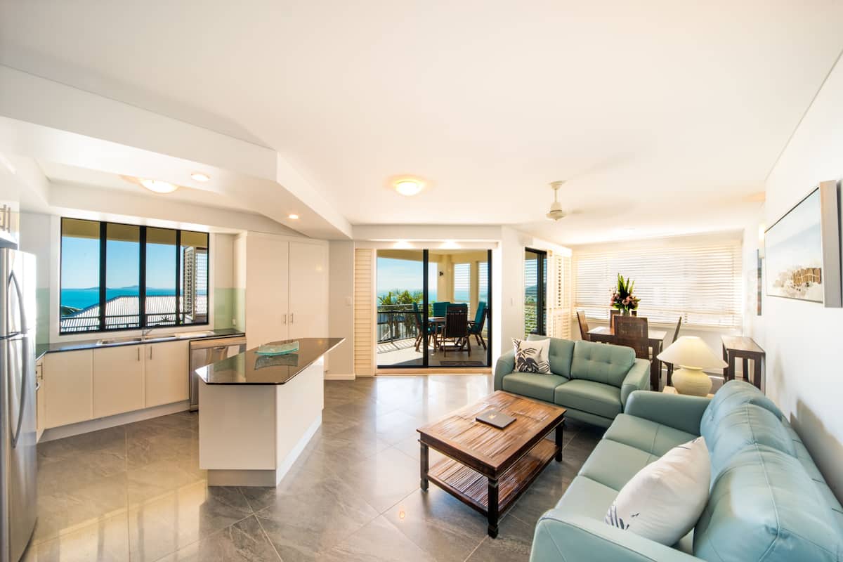 Una cocina moderna con vistas, un comedor con mesa y sillas, y una sala de estar con sofá y una mesa de centro.