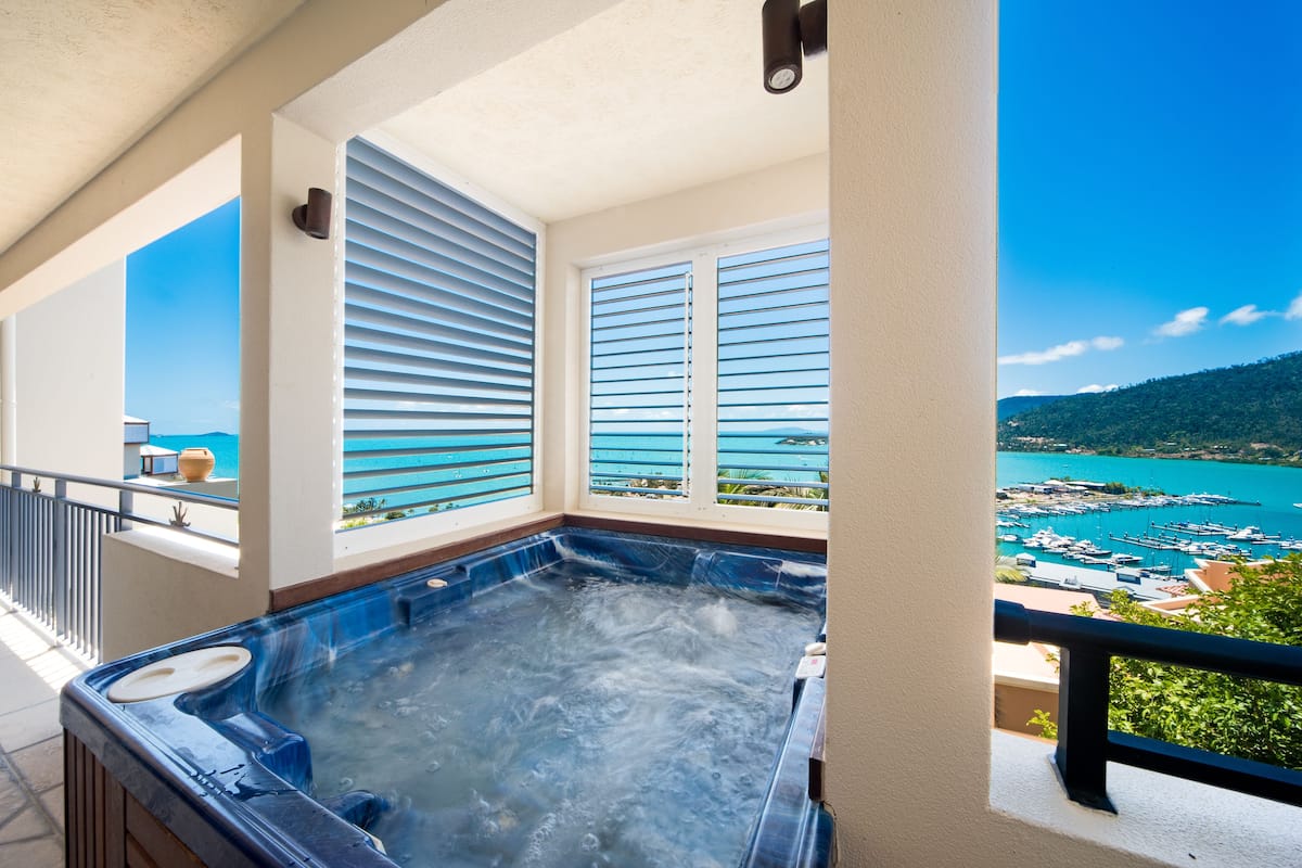Un jacuzzi en un balcón con vista a un puerto deportivo y al mar.