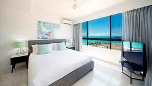 A modern hotel room with a large bed, a TV, and a balcony with a sea view. - Pinnacles (Airlie Beach)