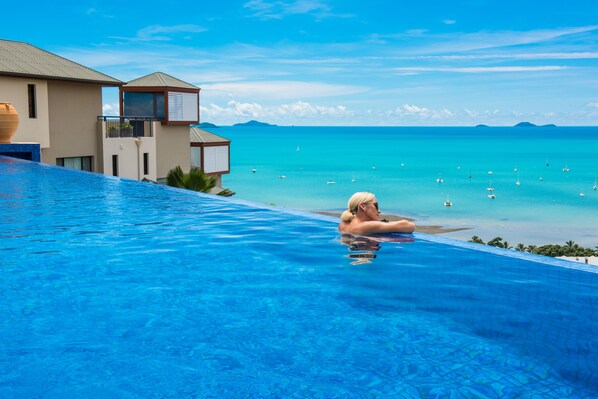 Una piscina con vistas al océano y un edificio con balcón.