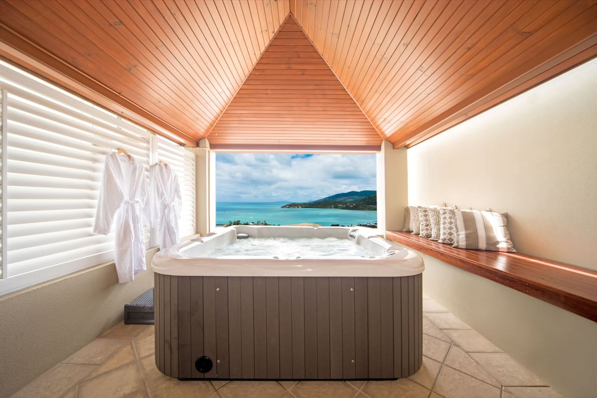 Un jacuzzi en una habitación con techo de madera y vista al mar.