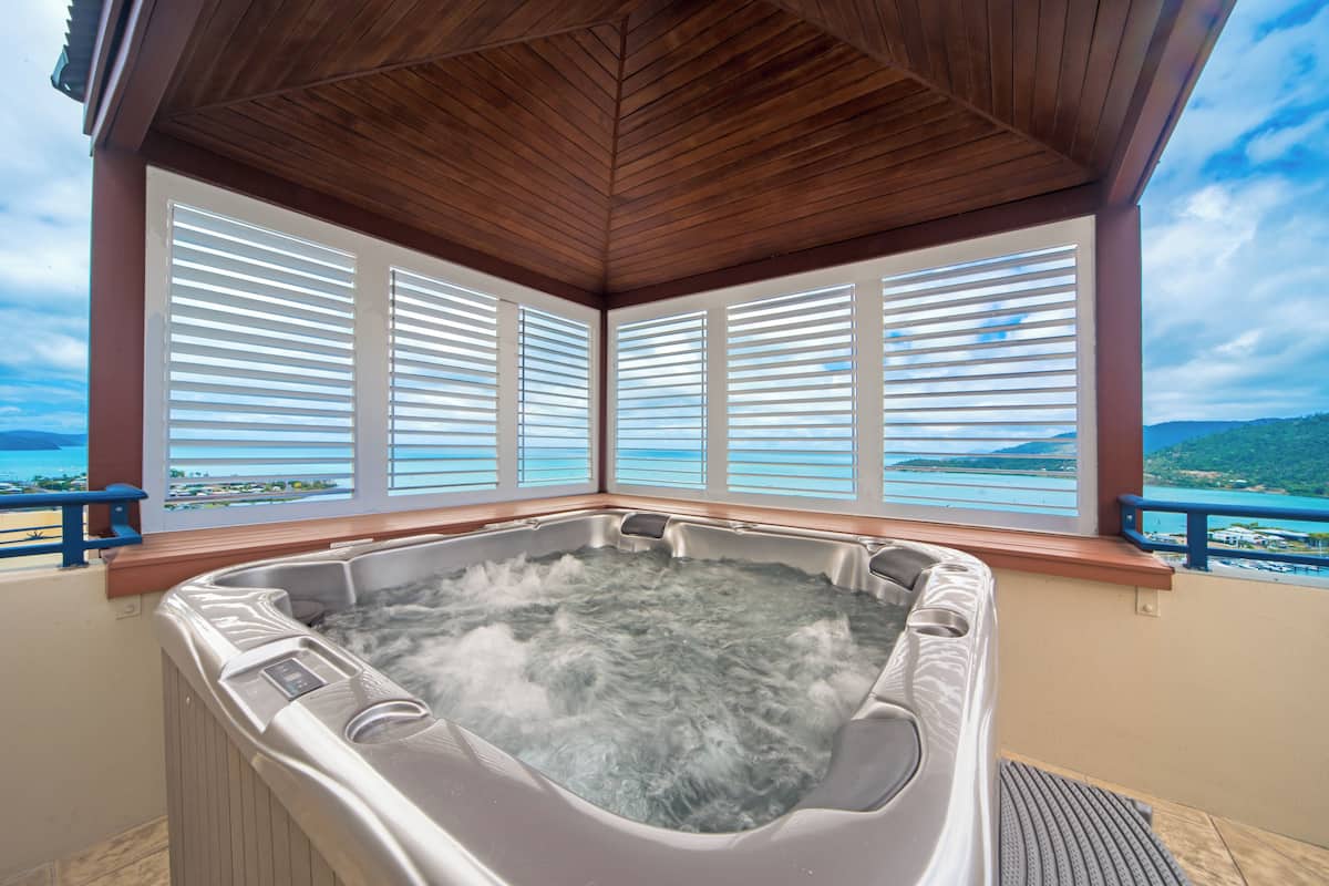 Un jacuzzi con techo de madera y amplias ventanas con vistas panorámicas.