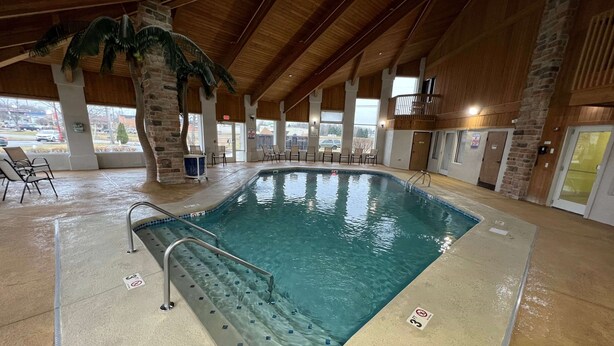 Una piscina interior con agua cristalina, un cartel de prohibido bucear y un puesto de socorrista.