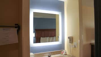 Une salle de bain équipée d’un lavabo, d’un miroir et d’un sèche-cheveux.