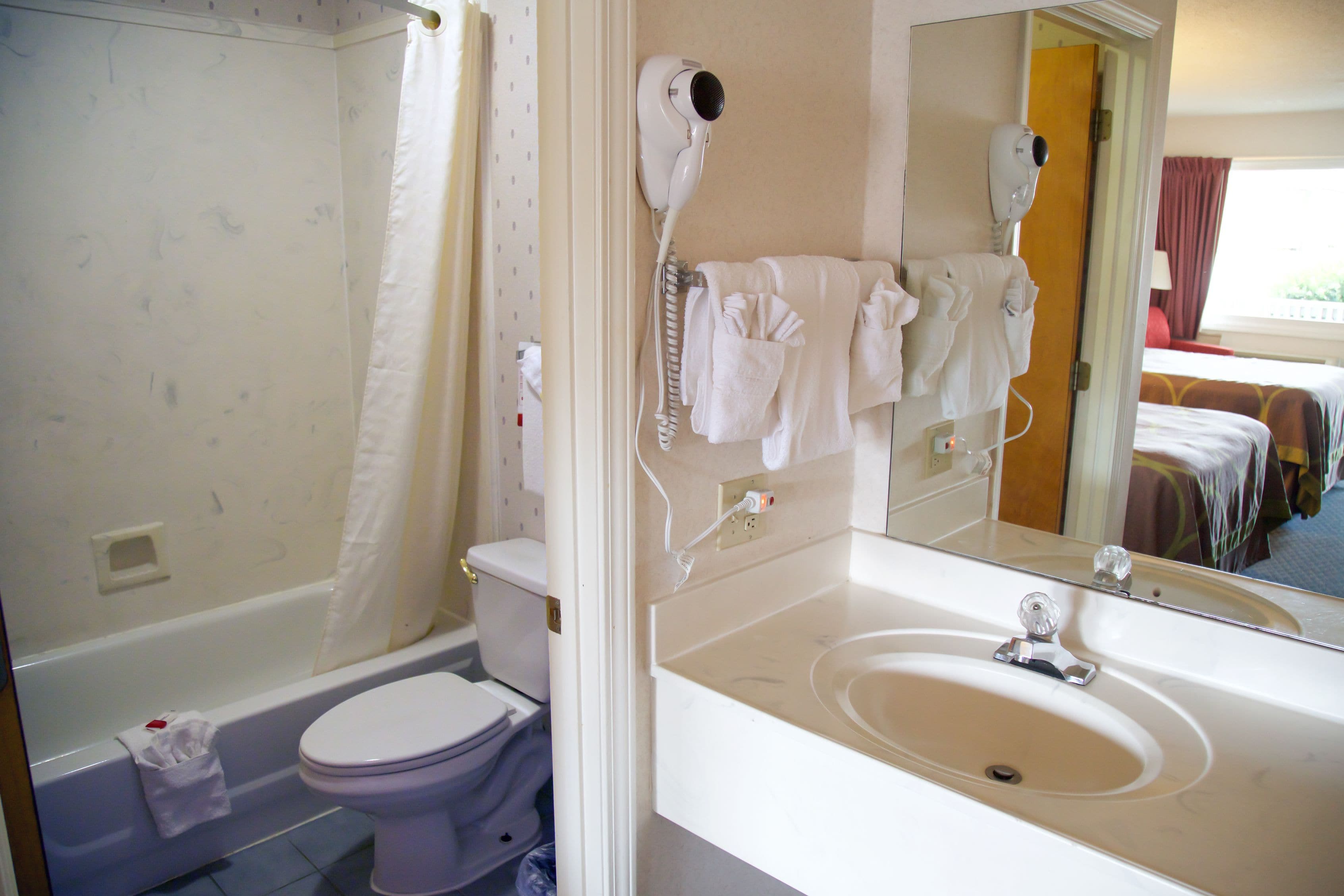 Un baño con inodoro, lavamanos, secador de pelo y espejo.