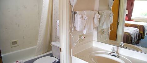 Un baño con inodoro, lavamanos, secador de pelo y espejo.
