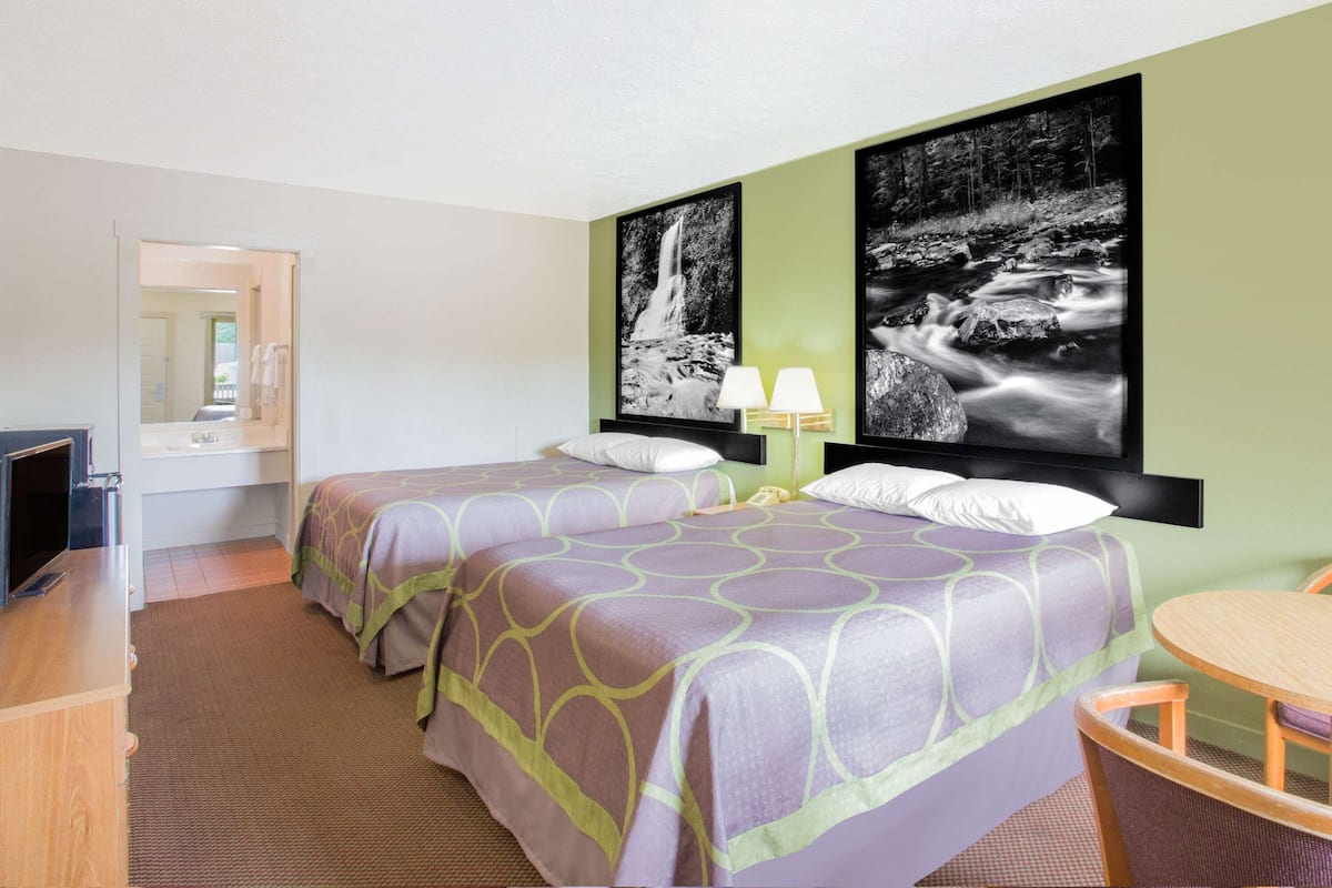 Une chambre d’hôtel avec deux lits, un bureau, une chaise et un téléviseur.