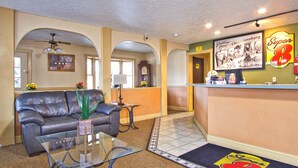 A lobby with a reception desk, a leather sofa, a glass coffee table, and a clock on the wall. - Super 8 by Wyndham Christiansburg (Christiansburg)