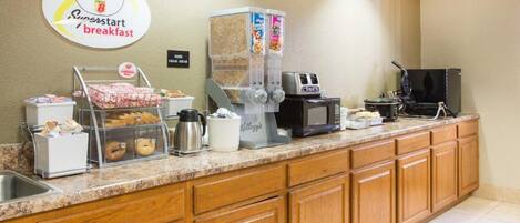 A breakfast station with a coffee machine, a microwave, and a cereal dispenser.