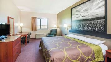 Een hotelkamer met een bed, een bureau, een stoel, een televisie en een groot raam.