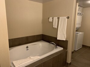 A bathroom with a bathtub, a towel rack with towels, and a washing machine.
