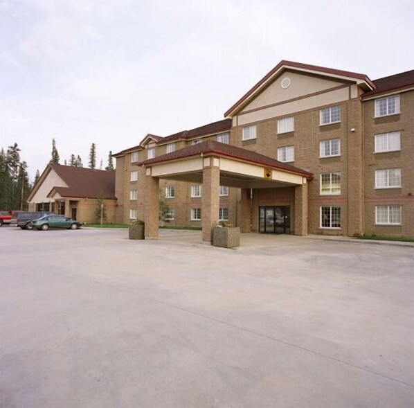 A multi-story hotel with a covered entrance and a parking lot.