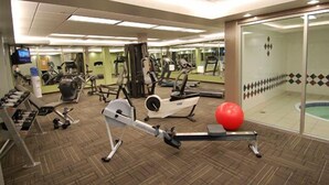 A gym with various exercise equipment, a treadmill, and a red exercise ball. - Woodlands Inn & Suites (Fort Nelson)