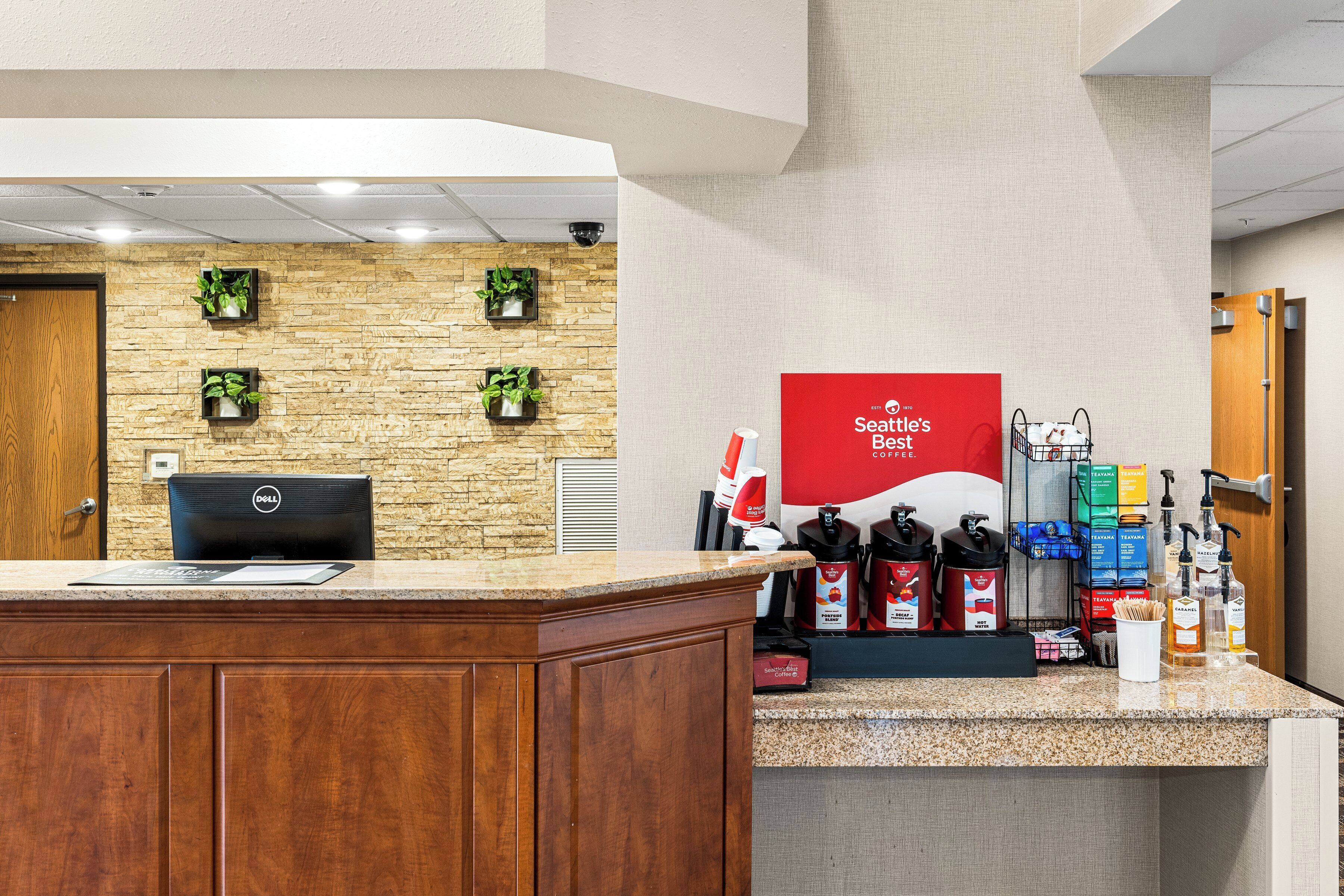 A reception area with a wooden desk, a Dell computer, and a coffee station with Seattle's Best branded items.