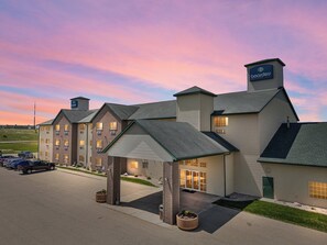 A hotel with a prominent boarder sign, multiple entry points, and a parking lot with several cars. - Boarders Inn & Suites by Cobblestone Hotels - Shawano (Shawano)